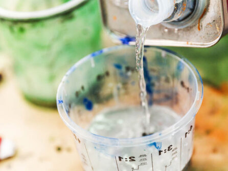 Thinners pouring into paint measuring cup. Wheel repair coatings being mixed